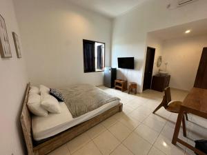 a bedroom with a bed and a desk and a television at Muno House in Seminyak
