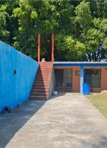 a house with a blue wall and stairs at Finca EL CHACHALACO in Agua Buena