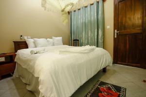 a bedroom with a large white bed and a window at Silent Patner Lodge in Arusha