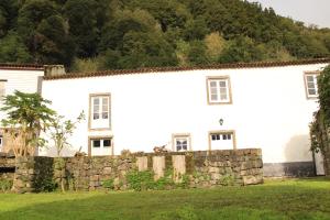 a white house with a stone fence in front of it at Aldeia do Sanguinho in Faial da Terra