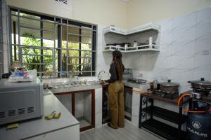 a woman standing in a kitchen preparing food at Silent Patner Lodge in Arusha