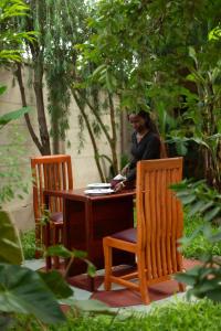 a woman sitting at a table with two chairs at Silent Patner Lodge in Arusha +2 photos