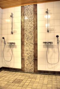 a bathroom with two showers and a tiled wall at PUUSTILANRANTA 4 A (5 mh) in Tahkovuori +13 photos