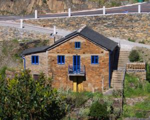 a brick house with blue windows and a balcony at Casa do Padrinho in Teixeira de Baixo