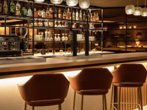 Eine Bar mit zwei Barhockern und Flaschen Alkohol in der Unterkunft Mercure Luxembourg Off Kirchberg in Luxemburg (Stadt)