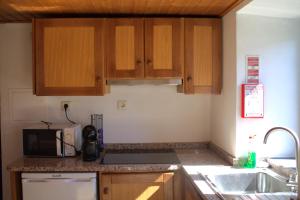 a kitchen with wooden cabinets and a microwave at Casa do Padrinho in Teixeira de Baixo