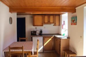 a kitchen with wooden cabinets and a table with a tableablish at Casa do Padrinho in Teixeira de Baixo