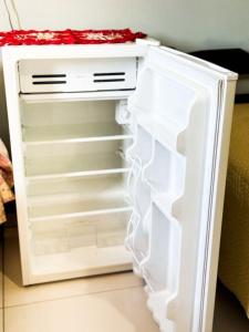 a white refrigerator with its door open in a room at Suítes em Bacaxá Saquarema in Saquarema +1 photo