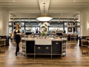 a woman walking past a bar in a restaurant at Fairmont Banff Springs in Banff