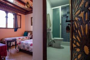 a bathroom with a toilet and a bed and a shower at Hotel Chams in Chefchaouen