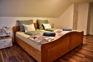 a bedroom with a wooden bed with green pillows at Gyömbér Tanya in Ásotthalom
