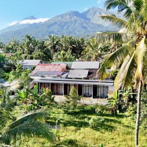 a house with palm trees and mountains in the background at Denis cozy homestay in Senaru