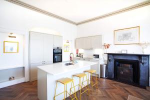 a kitchen with white cabinets and a kitchen island with yellow bar stools at Riversdale in Falmouth