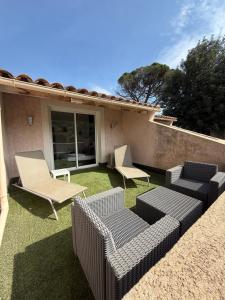 a patio with two chairs and wicker furniture on the grass at maison 6 personnes villa sofia in Sainte-Maxime