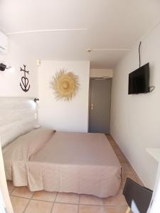 a bedroom with a bed and a flat screen tv at Hôtel Quai d'Azur in Le Grau-du-Roi