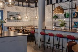 a restaurant with red stools at a counter and tables at Home Hotel Bristol in Arvika