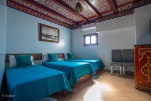 two beds in a room with blue walls at Hotel Chams in Chefchaouen