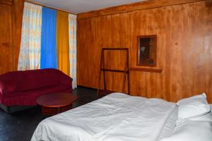 a bedroom with a bed and a red chair at Shiny cot resort in Nuwara Eliya +3 photos