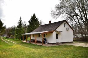 a small white house with a black roof at Gyömbér Tanya in Ásotthalom