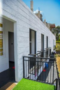 a white building with a balcony and grass at Shiny cot resort in Nuwara Eliya