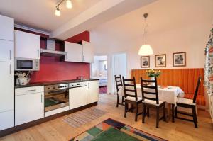una cocina con armarios blancos y una mesa con sillas. en Apartments Nindl en Neukirchen am Großvenediger