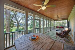 a screened porch with a wooden table and a ceiling fan at SM04: 4 Silver Moss in Kiawah Island