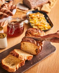 a person cutting a loaf of bread on a cutting board at Campanile Maubeuge in Maubeuge