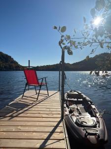 a boat and a chair on a dock on a lake at Gîte du Lac-à-la-Loutre - B&B in Huberdeau