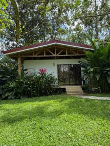 a small white house with a red roof at Casa Yami Lodge in Fortuna