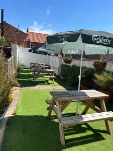 a picnic table with an umbrella in a garden at The Three Coopers in Bedale