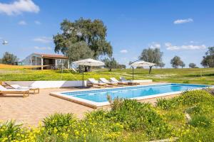 a swimming pool with lounge chairs and umbrellas at Monte do Sossego by Portugal Active in Ferreira do Alentejo