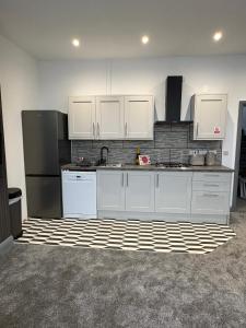 a kitchen with white cabinets and a black refrigerator at Spacious 4 Bed Retreat, 2 Bath, Sleeps 8 plus 2, Beach, Bars, Dinning, Shops, Golf, for Groups, Contractors or Families in Bournemouth