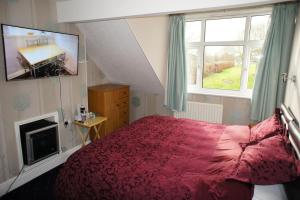 a bedroom with a red bed and a window at Abinger Guest House in Leicester