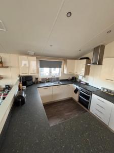 a large kitchen with white cabinets and a large window at Seaview Holiday Rentals - Pebble Beach in Whitstable