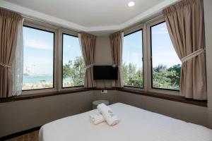 a bedroom with a bed with two white pillows in front of windows at Wangs Hotel Gurney Drive in George Town