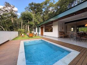 a house with a swimming pool on a wooden deck at Casa 08 Floresta Boa Vista - Piscina Privativa e Lounge com Deck em Meio à Natureza in Teresópolis