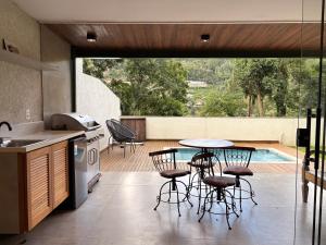 a kitchen with a table and chairs and a pool at Casa 08 Floresta Boa Vista - Piscina Privativa e Lounge com Deck em Meio à Natureza in Teresópolis