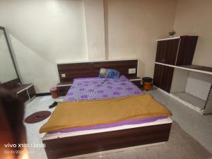 a bedroom with a bed with a wooden head board at HOTEL VISAVA GARDEN & LODGINg in Vaghunde Budrukh