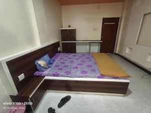 a bedroom with a bed with a purple comforter at HOTEL VISAVA GARDEN & LODGINg in Vaghunde Budrukh