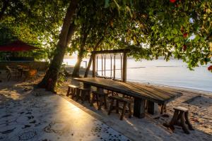 a wooden bench under a tree next to the water at La Patria Chica in Sampong