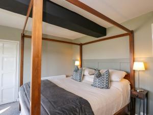 a bedroom with a canopy bed with pillows on it at 3 Woods Farm House in Chippenham
