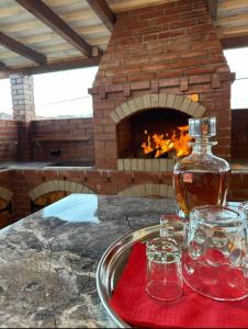 a bottle of whiskey and two glasses on a table with a fireplace at Casa Cu Lavandă in Valea Drăganului