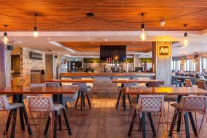 a restaurant with wooden tables and chairs and a bar at Village Hotel Birmingham Walsall in Walsall