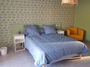 a bed with a blue comforter and a chair in a bedroom at les terrasses d'arutoli in Porto-Vecchio