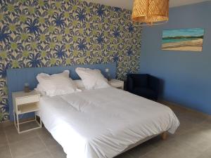 a bedroom with a white bed and a blue wall at les terrasses d'arutoli in Porto-Vecchio