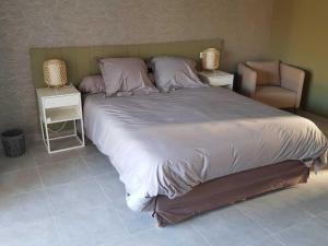 a bedroom with a large bed and a chair at les terrasses d'arutoli in Porto-Vecchio