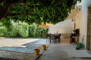 a patio with a table and chairs under a tree at Maison Pamplemousse in Arles