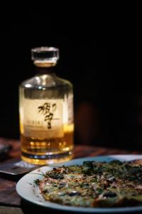 a bottle of whiskey and a pizza on a table at Kasba Homes in Kalgha