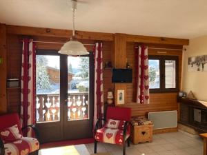 a living room with two chairs and a sliding glass door at Appartement les Carroz d'Arraches in Les Carroz d'Araches