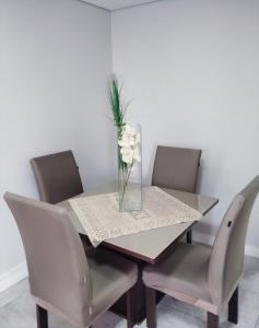 a dining room table with chairs and a vase of flowers at Apartamento no centro de Caxias com elevador e garagem in Caxias do Sul +16 photos